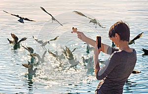 Young woman taking a picture with her phone of Flock of seagulls