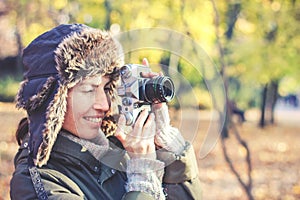 Young woman taking pictures in the autumn park.