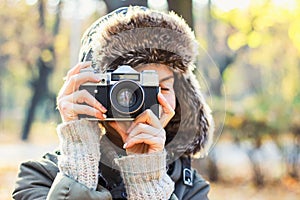 Young woman taking pictures in the autumn park.