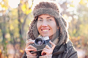 Young woman taking pictures in the autumn park.