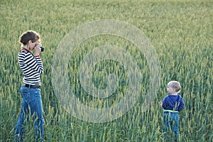 Young woman taking pictures of a child in a field