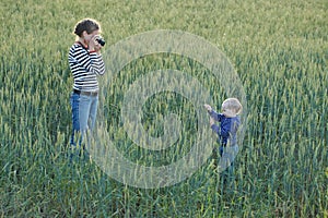 Young woman taking pictures of a child in a field
