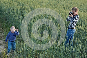 Young woman taking pictures of a child in a field