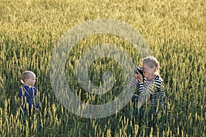 Young woman taking pictures of a child in a field