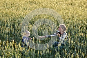 Young woman taking pictures of a child in a field