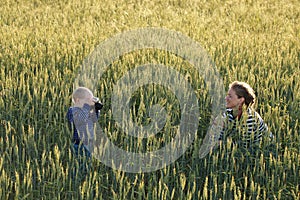 Young woman taking pictures of a child in a field