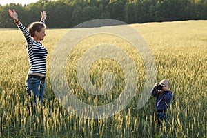 Young woman taking pictures of a child in a field