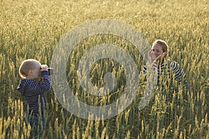 Young woman taking pictures of a child in a field