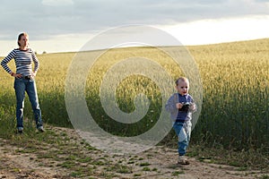 Young woman taking pictures of a child in a field