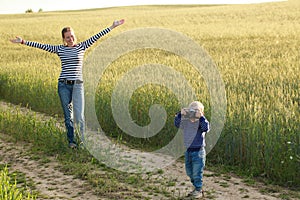 Young woman taking pictures of a child in a field