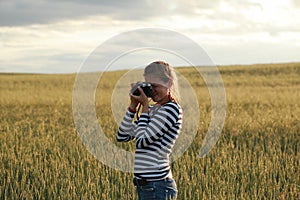 Young woman taking pictures of a child in a field