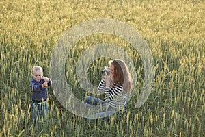 Young woman taking pictures of a child in a field