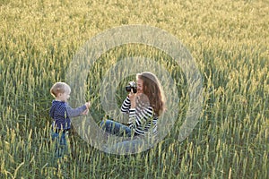 Young woman taking pictures of a child in a field