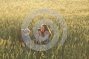 Young woman taking pictures of a child in a field