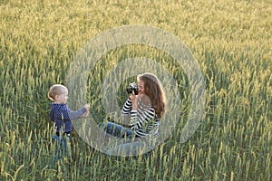 Young woman taking pictures of a child in a field