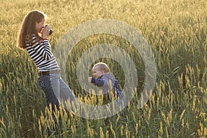 Young woman taking pictures of a child in a field