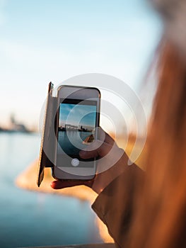 Young Woman taking pictures of Cologne with her smartphone