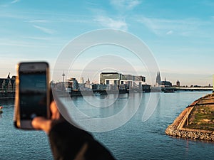 Young Woman taking pictures of Cologne with her smartphone