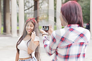 Young woman taking pictures of her friends in the park.