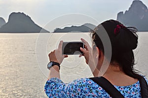 young woman taking pictures of the morning sea view with mobile phone