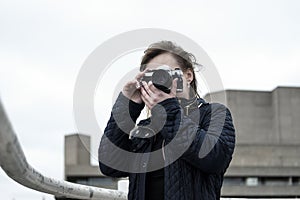 Young woman taking pictures with a vintage film camera in riverside London