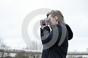 Young woman taking pictures with a vintage film camera in riverside London