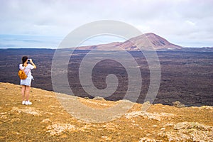 Young woman taking pictures of a volcano