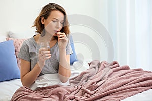 Young woman taking pill in bed