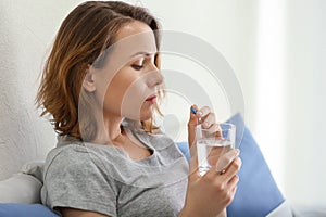 Young woman taking pill in bed