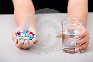 Young woman taking pill or drug with glass of water,