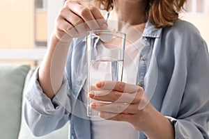 Young woman taking pill, indoors