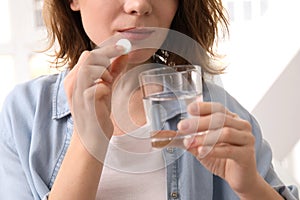 Young woman taking pill, indoors