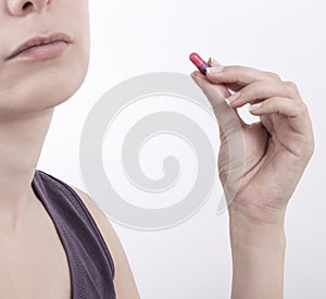 Young woman taking pill over white background