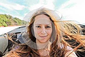 Young woman taking a selfie in a convertible