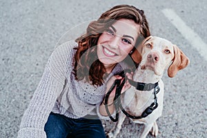 young woman taking a selfie with mobile phone with her dog at the street. autumn season