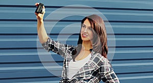 Young woman taking selfie picture by camera over blue background