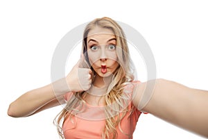 Young woman taking selfie and showing thumbs up