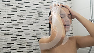 Young woman taking a shower and washing her hair in the bathroom