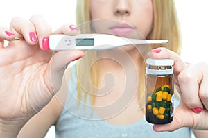 Young woman taking temperature and pills