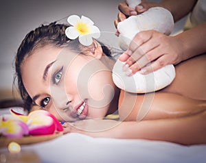 Young woman is taking Thai Herbal ball hot compress massage in an authetic spa authentic