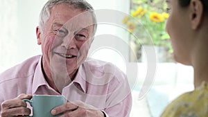 Young Woman Taking Time To Visit Senior Male Neighbor