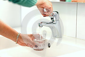 Young woman taking water direct from the tab to drink, showing its`s safety to drink tab  water and cares for world environment to