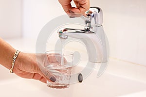 Young woman taking water direct from the tab to drink, showing its`s safety to drink tab  water and cares for world environment to