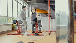 Young woman talking with coacher in workout room