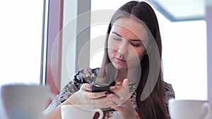 Young woman talking with friends and using smartphone in cafe