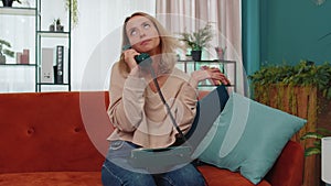 Young woman talking with friends on wired telephone fooling, making silly faces, conversation call