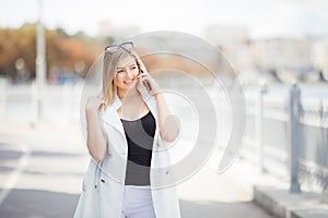 Young woman talking on her mobile phone listening to the conversation , she stands outdoors on granite embankment against a river