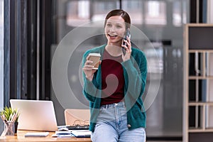 A young woman talking on her smartphone and holding a cup of coffee