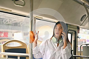 Young woman talking on mobile phone while traveling by bus. City life and transportation concept