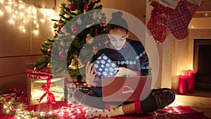 Young woman is talking online with her family using laptop on New Years night. She is sitting near decorated christmas